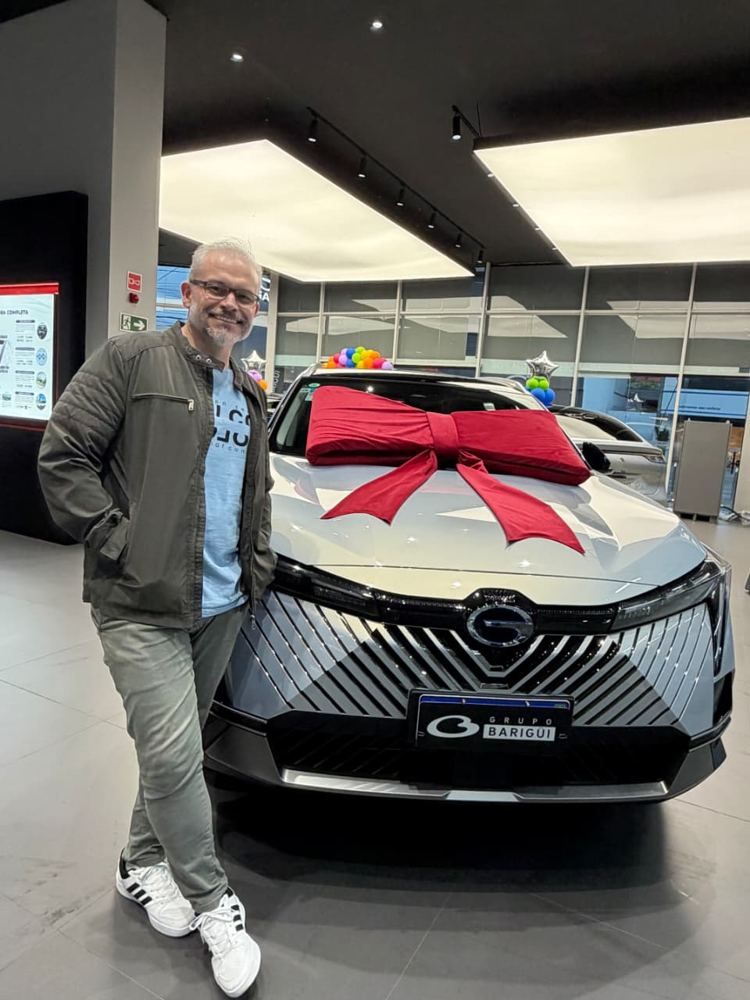 Cliente na concessionária ao lado do carro novo com laço vermelho